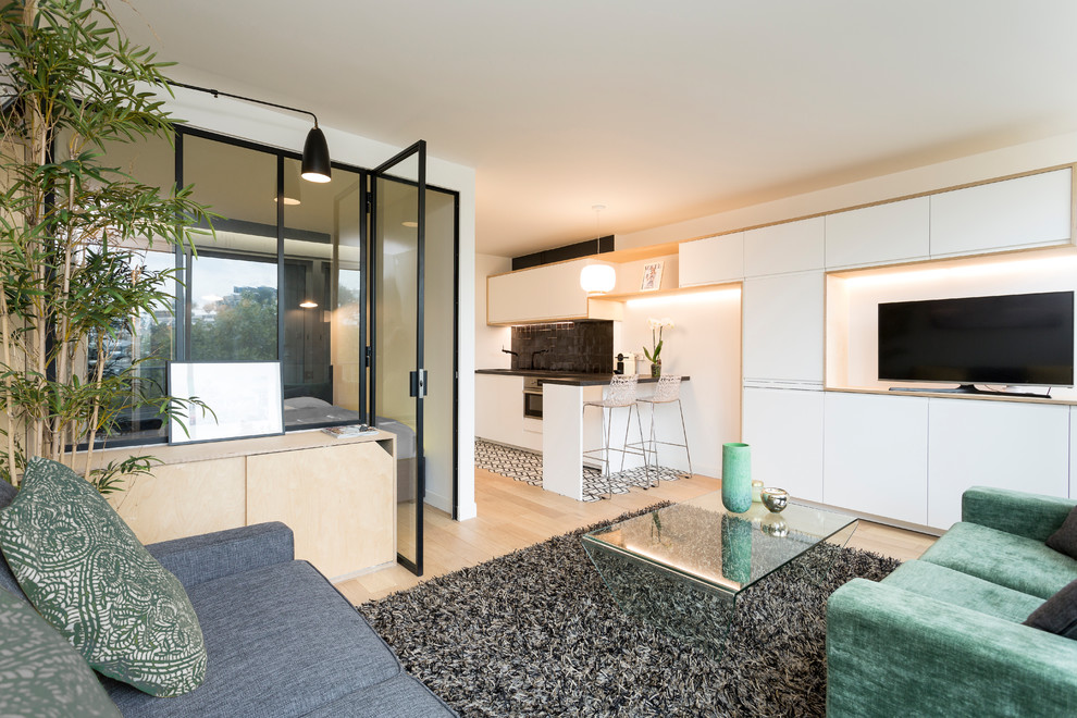 Example of a small danish open concept light wood floor living room design in Paris with green walls and a tv stand