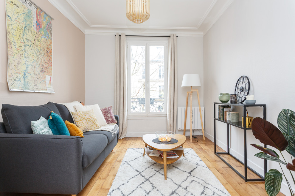 Foto de salón escandinavo sin chimenea y televisor con paredes blancas, suelo de madera clara y suelo beige