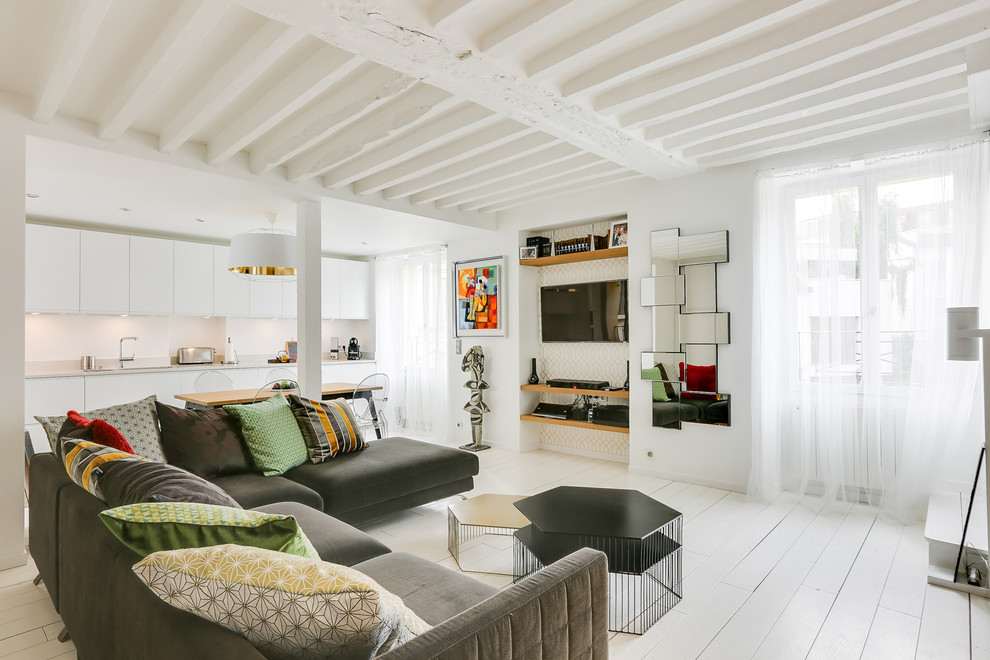 Cette image montre un salon design ouvert avec un mur blanc, un téléviseur encastré et un sol blanc.