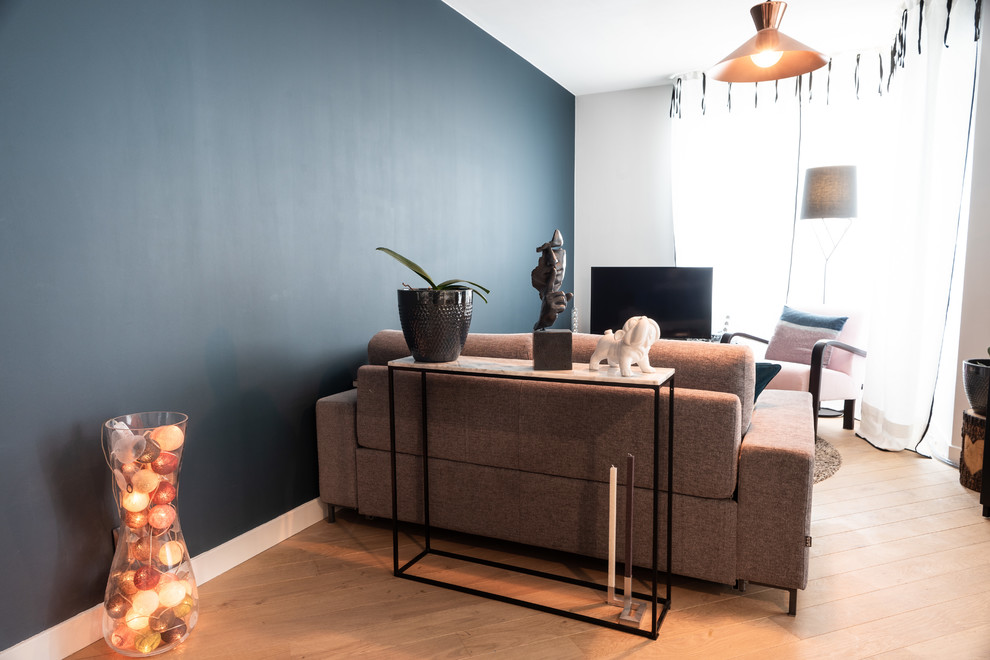 Exemple d'un salon tendance avec un mur bleu et parquet clair.