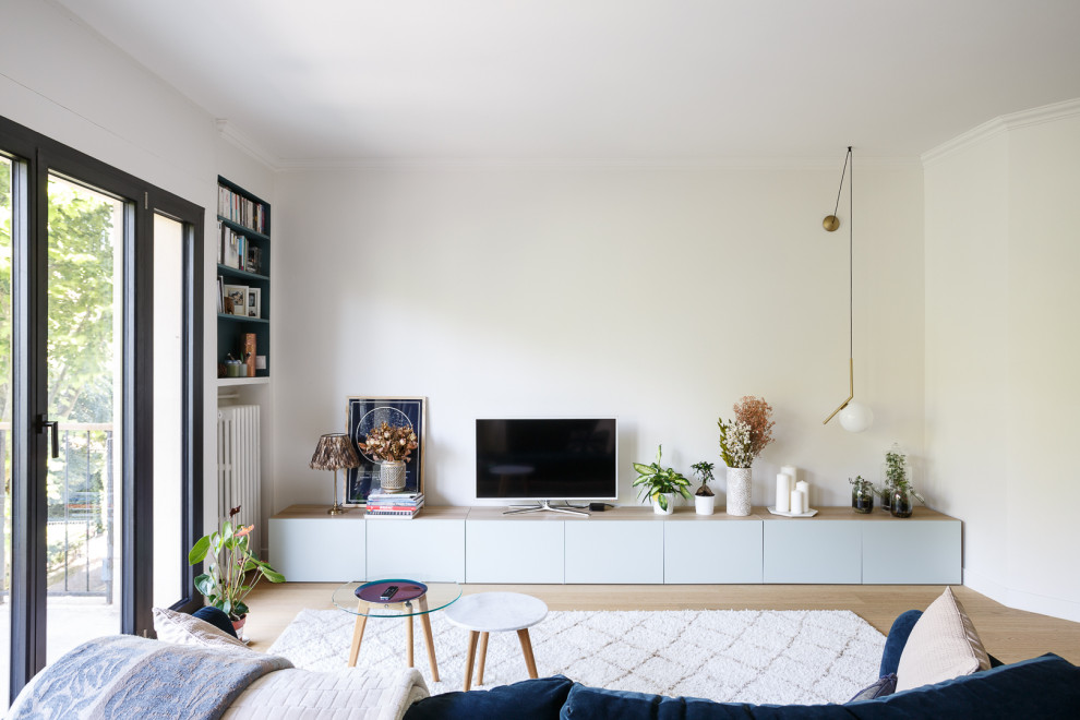 Cette photo montre un salon tendance de taille moyenne et ouvert avec parquet clair, aucune cheminée, un téléviseur indépendant, un sol beige et un mur blanc.