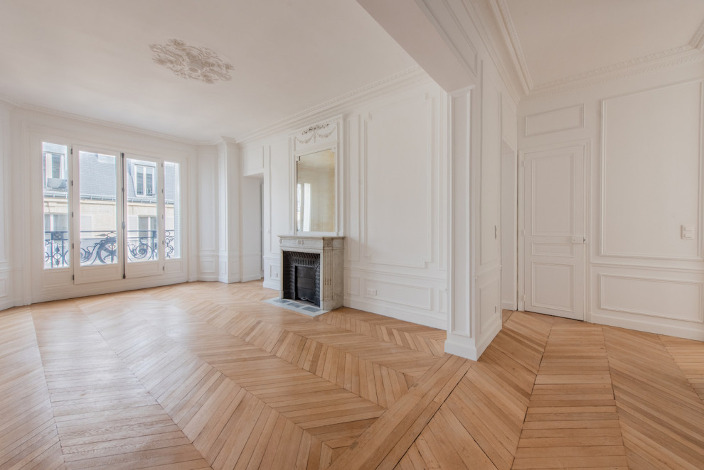 パリにある高級な広いトランジショナルスタイルのおしゃれな独立型リビング (白い壁、無垢フローリング、標準型暖炉、石材の暖炉まわり、ベージュの床) の写真