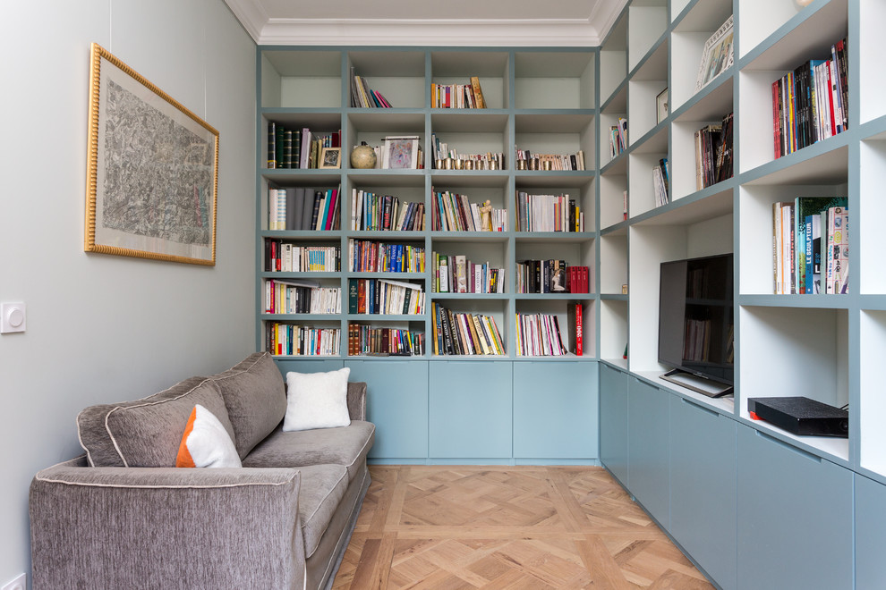 Immagine di un soggiorno minimal di medie dimensioni e chiuso con libreria, pareti blu, parquet chiaro, nessun camino, TV autoportante e pavimento beige