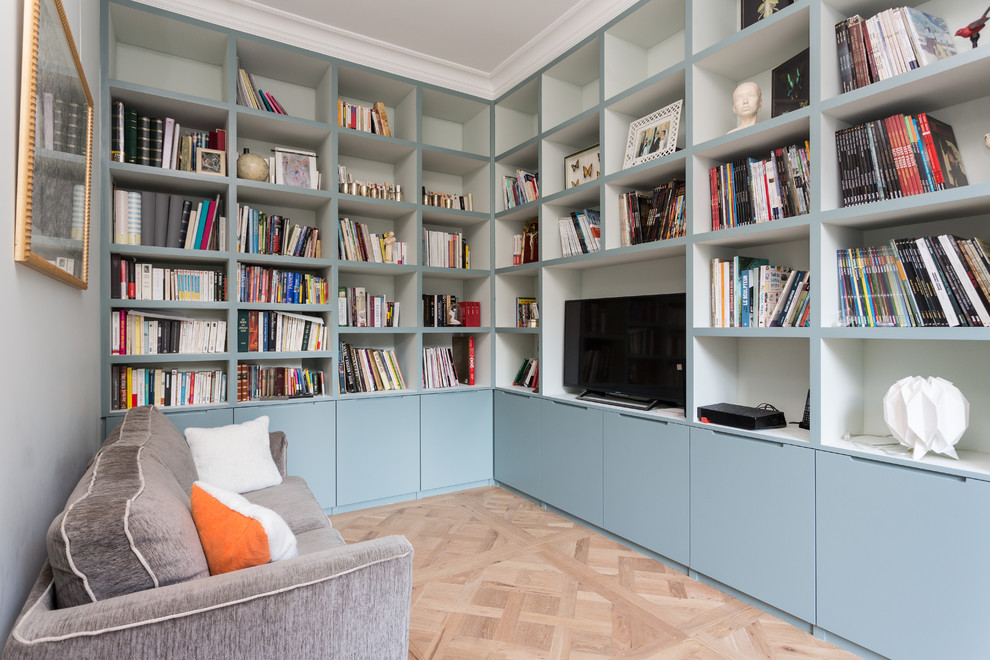 Idee per un soggiorno design di medie dimensioni e chiuso con parquet chiaro, pavimento beige, libreria, pareti blu, nessun camino e TV autoportante