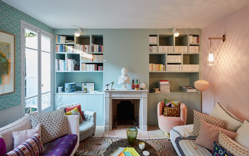Cette photo montre un salon chic avec une bibliothèque ou un coin lecture, un mur multicolore, une cheminée standard, un manteau de cheminée en brique, aucun téléviseur et éclairage.