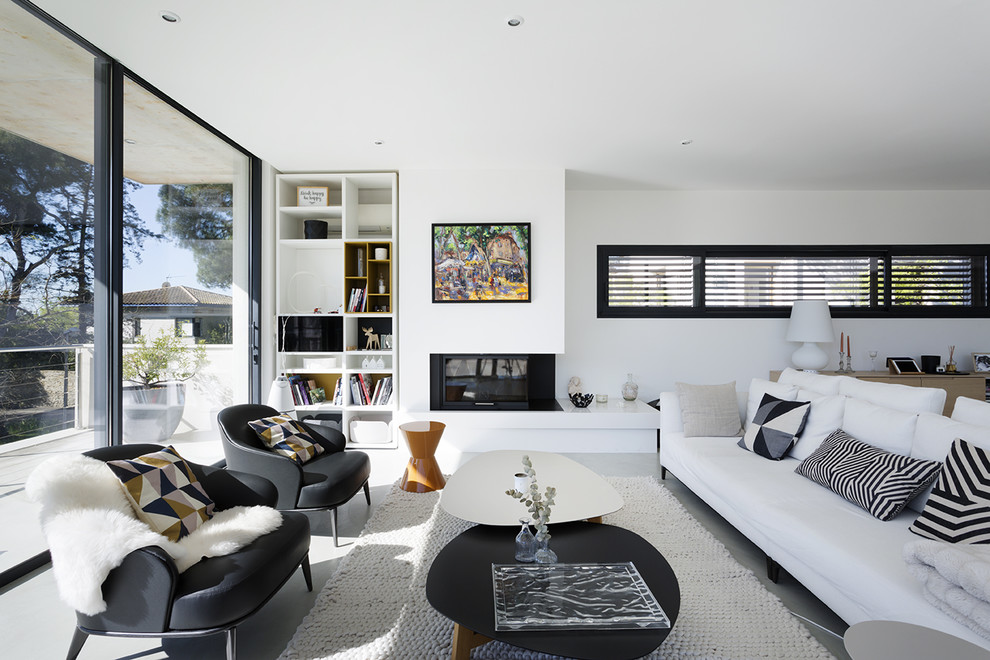 Foto di un soggiorno contemporaneo con sala formale, pareti bianche, pavimento in cemento, camino classico e pavimento grigio
