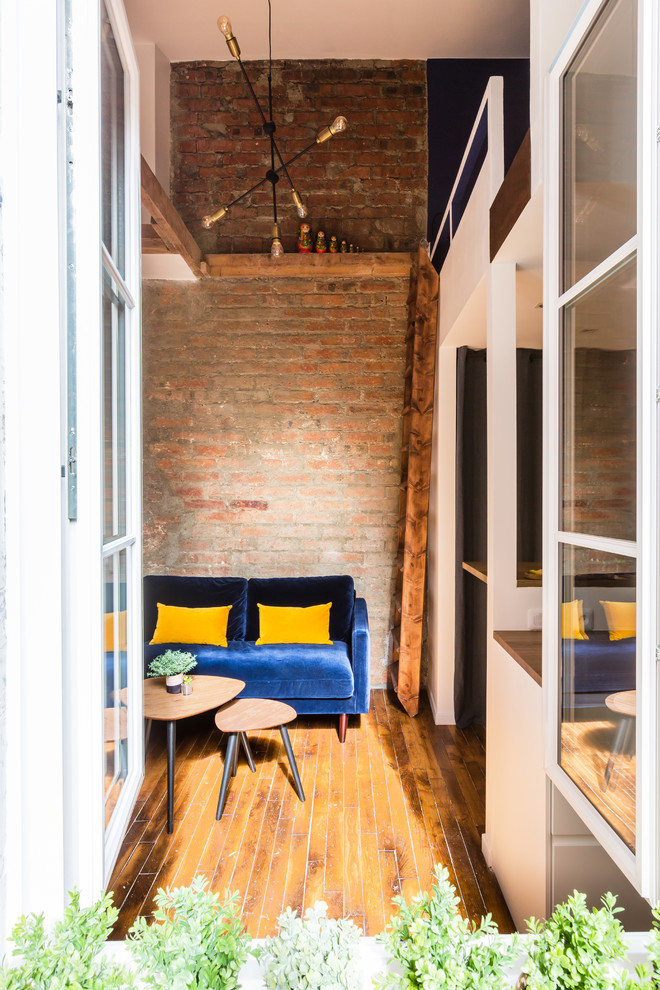 Imagen de salón con barra de bar tipo loft industrial pequeño sin chimenea con paredes azules, suelo de madera en tonos medios, televisor colgado en la pared y suelo marrón