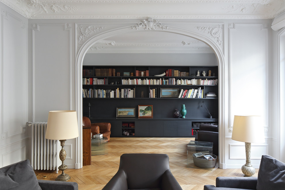 Ejemplo de biblioteca en casa abierta actual grande con paredes blancas, suelo de madera clara, todas las chimeneas, televisor independiente y arcos
