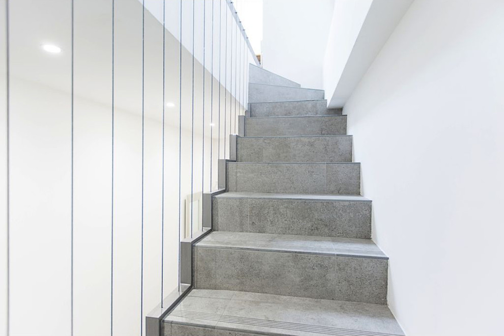 Ejemplo de escalera en L actual de tamaño medio con escalones con baldosas, contrahuellas con baldosas y/o azulejos y barandilla de cable