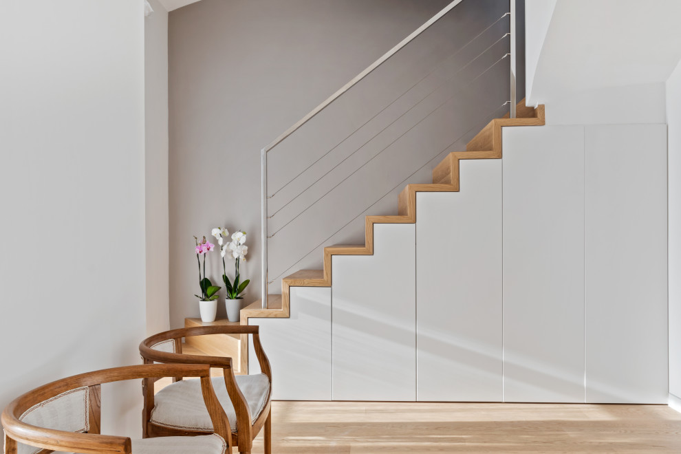 На фото: угловая деревянная лестница среднего размера в современном стиле с деревянными ступенями, металлическими перилами и кладовкой или шкафом под ней