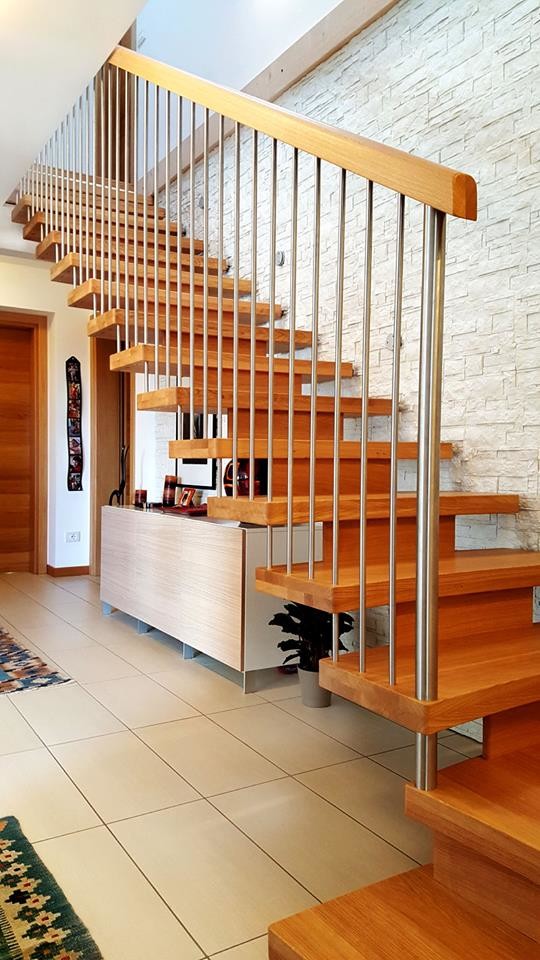 Imagen de escalera suspendida moderna grande con escalones de madera pintada, contrahuellas de madera pintada y barandilla de varios materiales