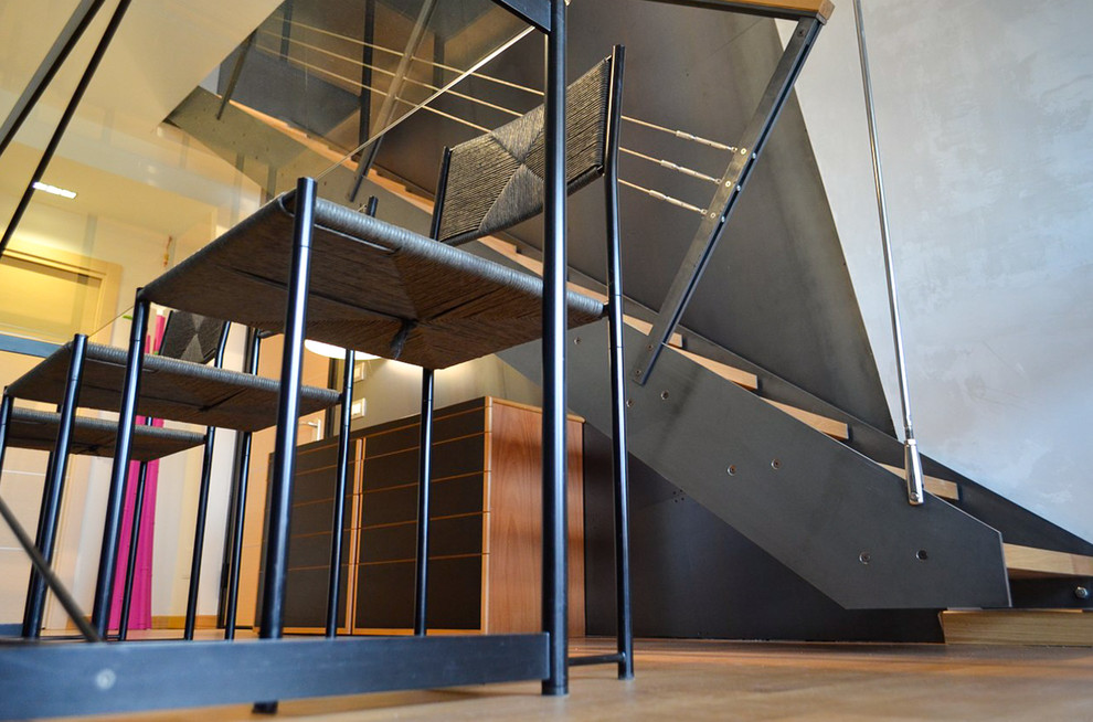 Cette image montre un escalier sans contremarche flottant minimaliste avec des marches en bois et un garde-corps en câble.