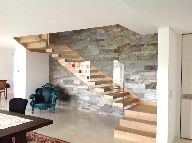 На фото: большая п-образная лестница в современном стиле с деревянными ступенями и стеклянными перилами без подступенок