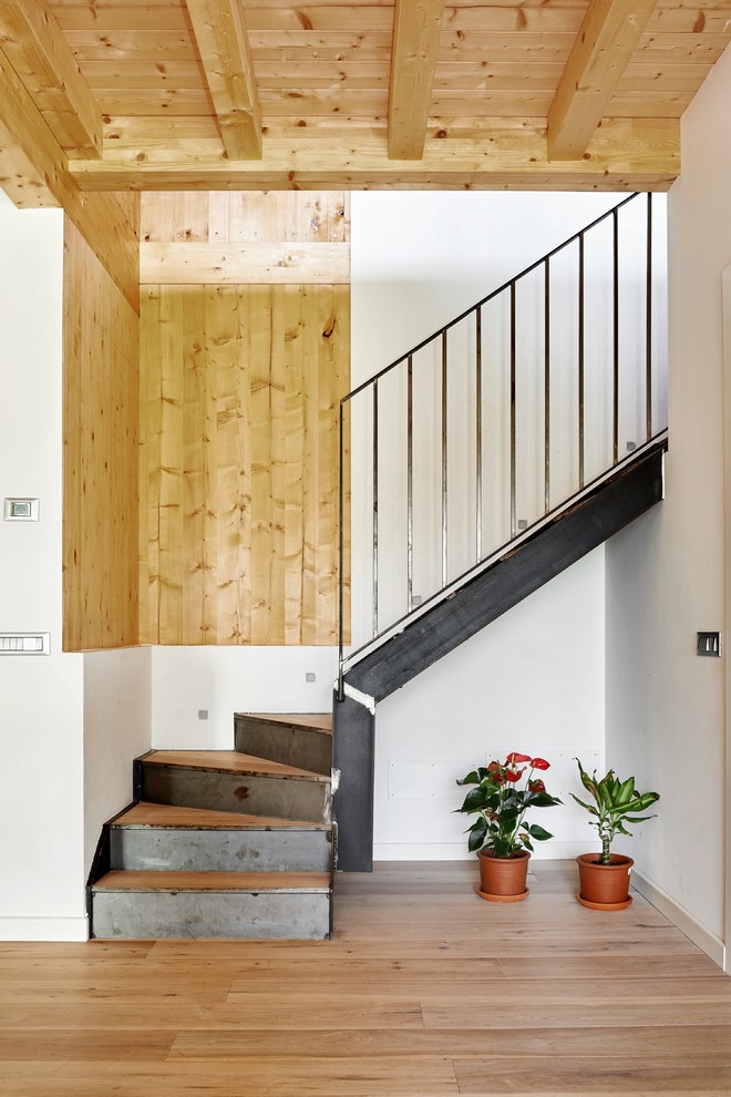 Inspiration pour un escalier design en L de taille moyenne avec des marches en bois, des contremarches en métal et un garde-corps en métal.