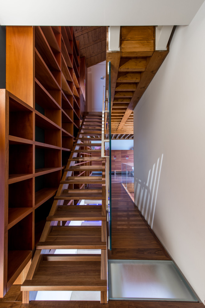 Imagen de escalera recta contemporánea de tamaño medio sin contrahuella con escalones de madera pintada y barandilla de vidrio