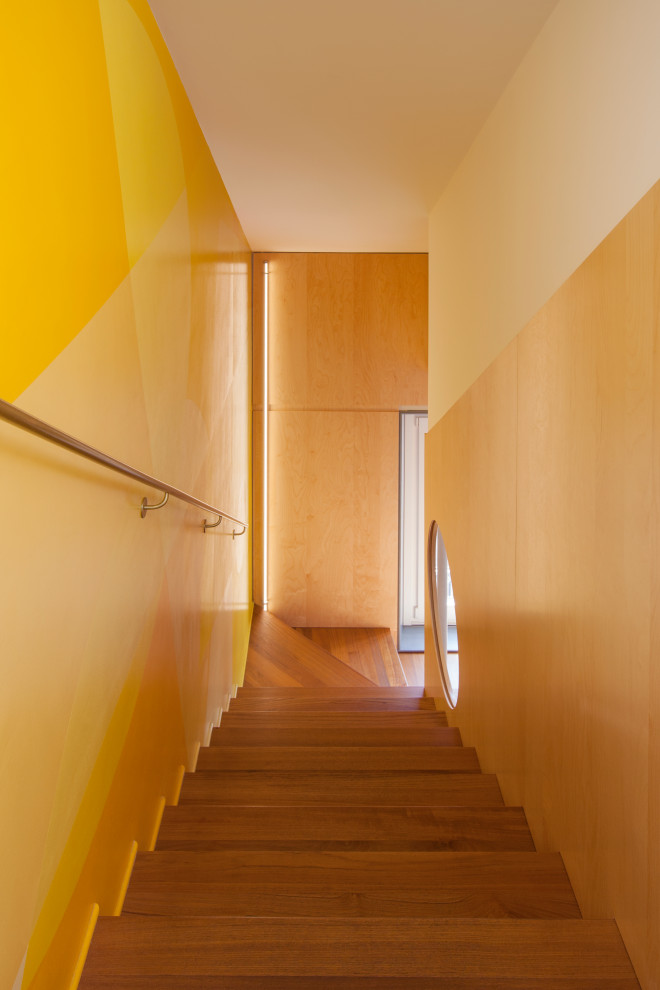 Immagine di una scala a "L" design di medie dimensioni con pedata in legno, parapetto in metallo e pareti in legno