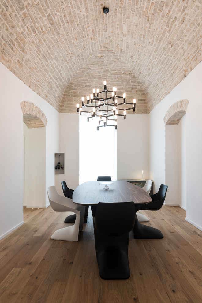 Esempio di una sala da pranzo mediterranea con pareti bianche, pavimento in legno massello medio e pavimento marrone