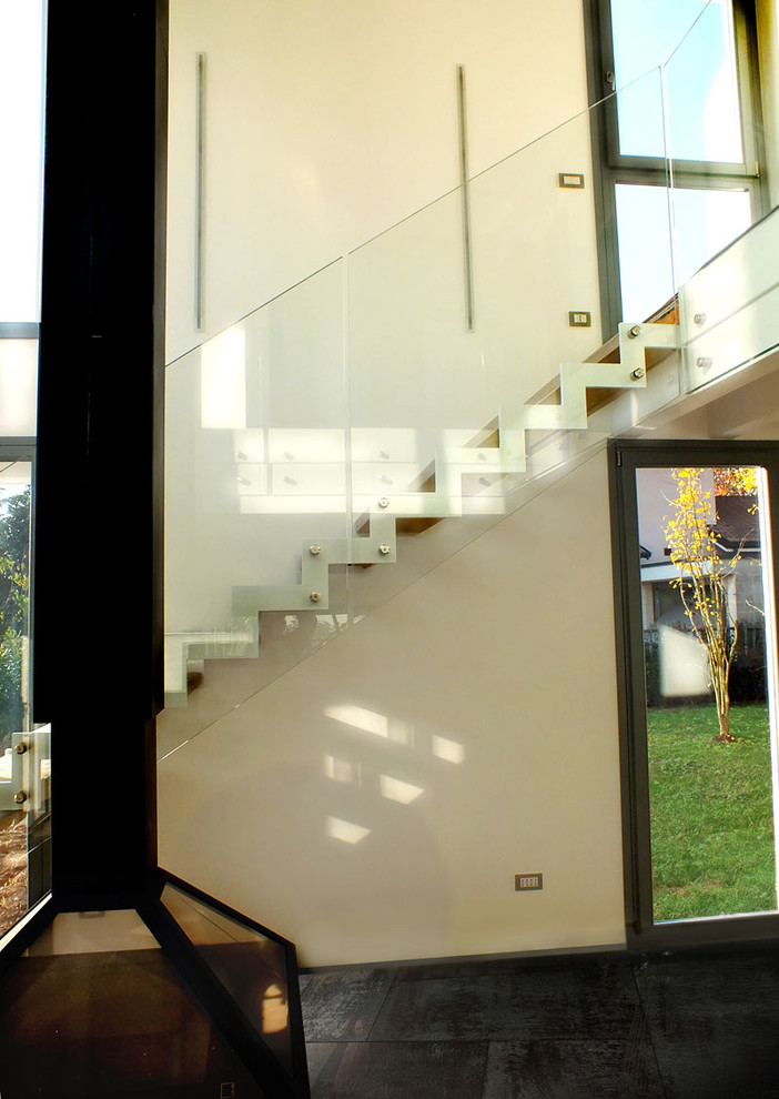 Ejemplo de escalera en L contemporánea grande sin contrahuella con escalones de madera y barandilla de vidrio