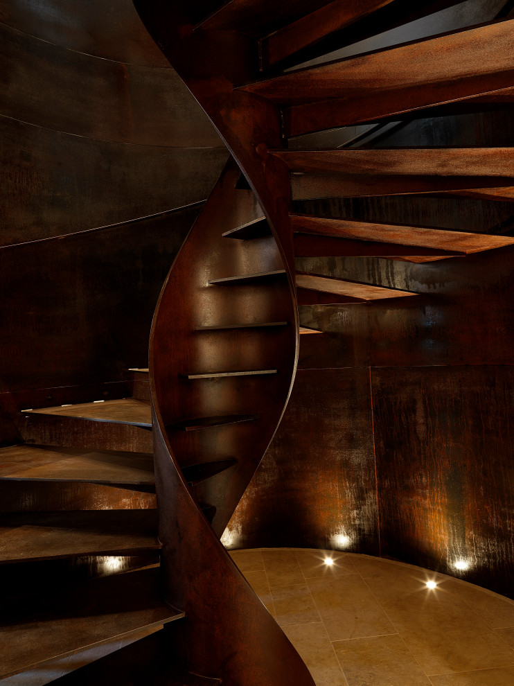 Cette image montre un grand escalier hélicoïdal urbain avec des marches en métal et un garde-corps en métal.