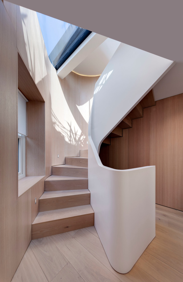 Aménagement d'un escalier courbe contemporain avec des marches en bois et des contremarches en bois.