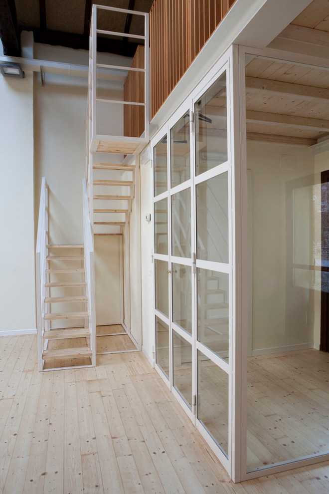 Kleine Moderne Holztreppe in U-Form mit offenen Setzstufen und Stahlgeländer in Mailand