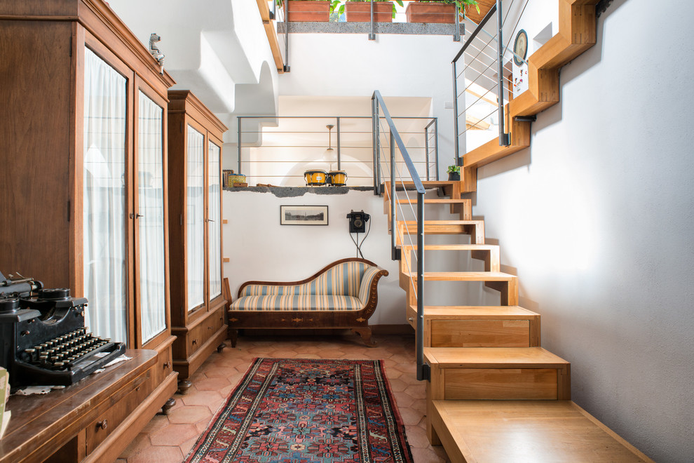 На фото: п-образная лестница в средиземноморском стиле с деревянными ступенями и перилами из тросов без подступенок с