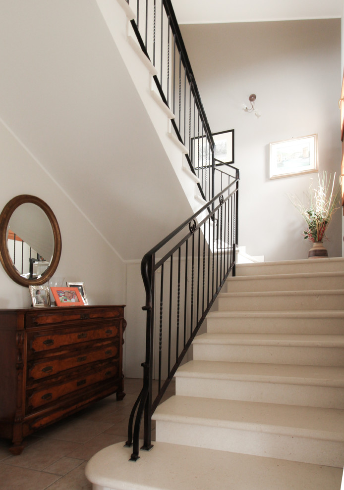 Ejemplo de escalera en U clásica de tamaño medio con escalones de mármol, contrahuellas de mármol y barandilla de metal