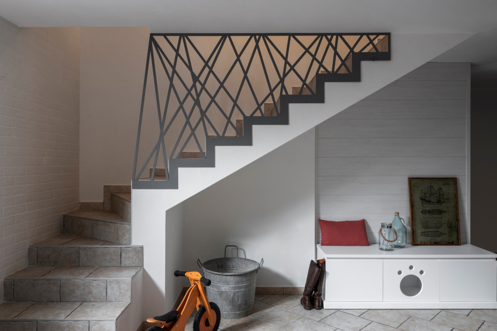 Cette image montre un petit escalier carrelé craftsman en L avec des contremarches carrelées et un garde-corps en métal.