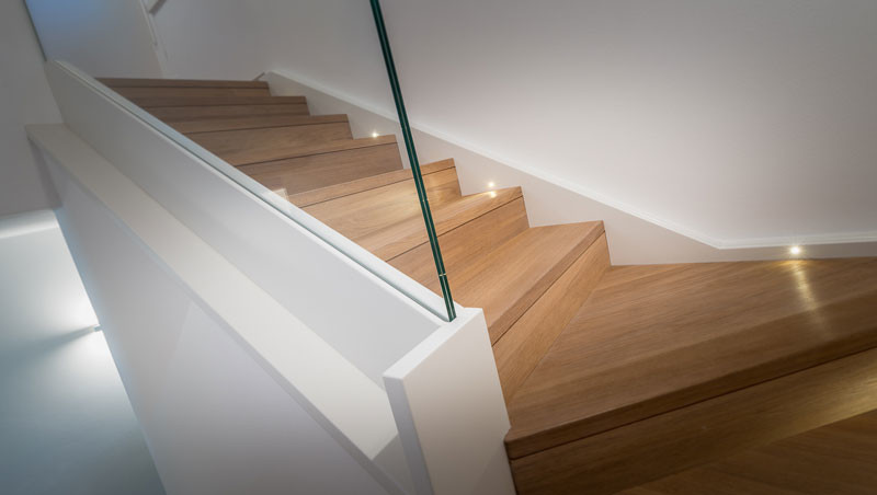 Imagen de escalera en U minimalista grande con escalones de madera, contrahuellas de madera y barandilla de vidrio