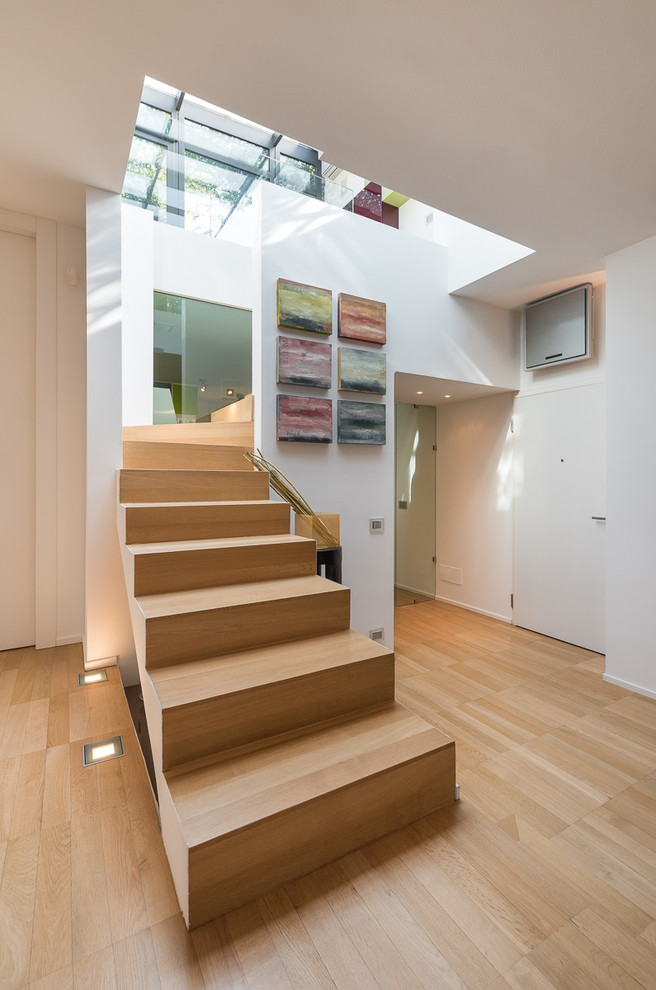 This is an example of a medium sized contemporary wood u-shaped staircase in Milan with wood risers.