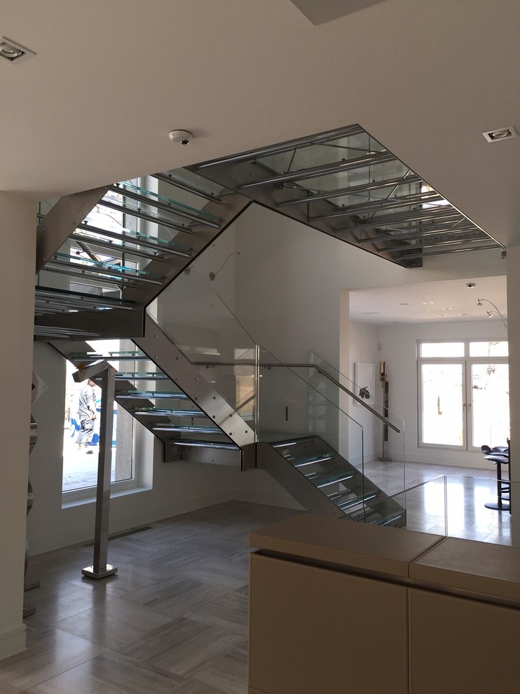 Cette image montre un escalier urbain en U de taille moyenne avec des marches en verre et des contremarches en métal.