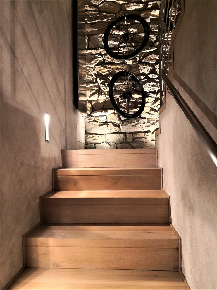Cette image montre un escalier design en U de taille moyenne avec des marches en bois, des contremarches en métal et un garde-corps en métal.