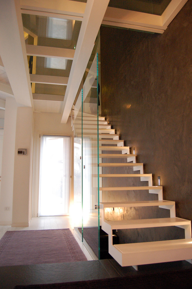 Cette photo montre un escalier sans contremarche moderne en L avec des marches en métal et un garde-corps en verre.