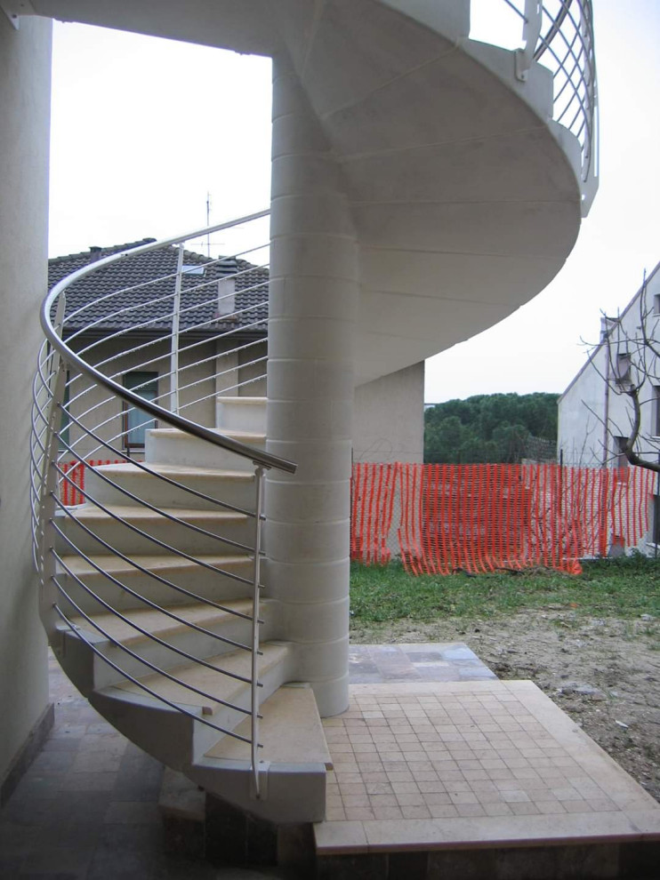 Bild på en funkis spiraltrappa i marmor, med sättsteg i betong och räcke i metall