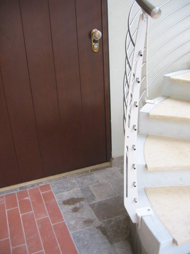 Contemporary spiral metal railing staircase in Rome with marble treads and concrete risers.