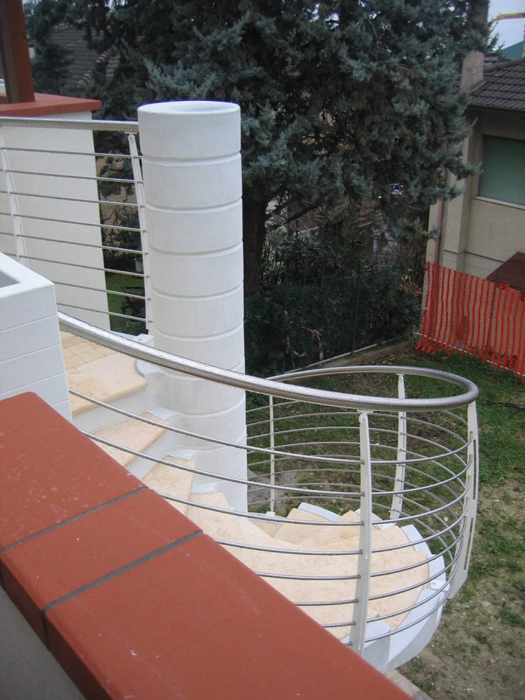 На фото: винтовая бетонная лестница в современном стиле с мраморными ступенями и металлическими перилами с