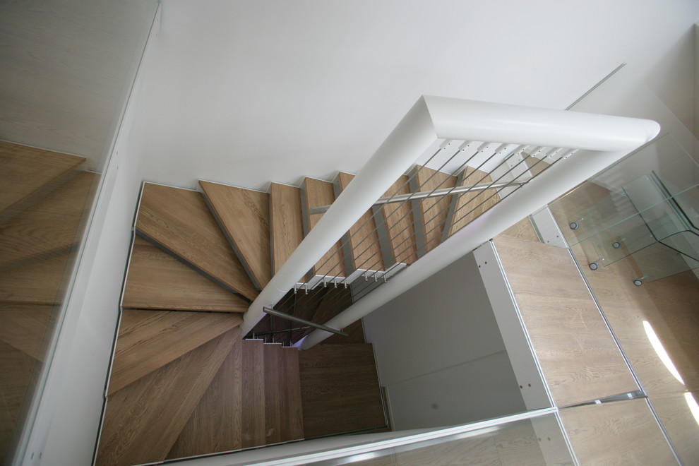 Imagen de escalera suspendida minimalista grande sin contrahuella con escalones de madera pintada y barandilla de vidrio