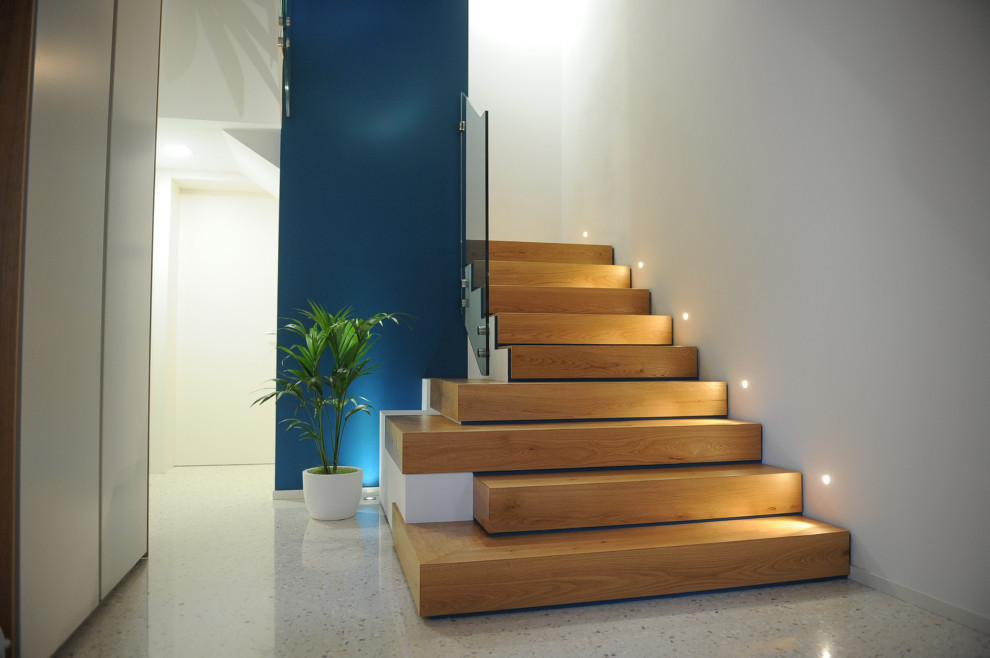 Inspiration pour un grand escalier design en L avec des marches en bois, des contremarches en bois et un garde-corps en verre.