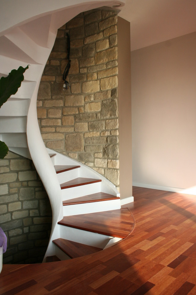 На фото: маленькая винтовая бетонная лестница в средиземноморском стиле с деревянными ступенями для на участке и в саду