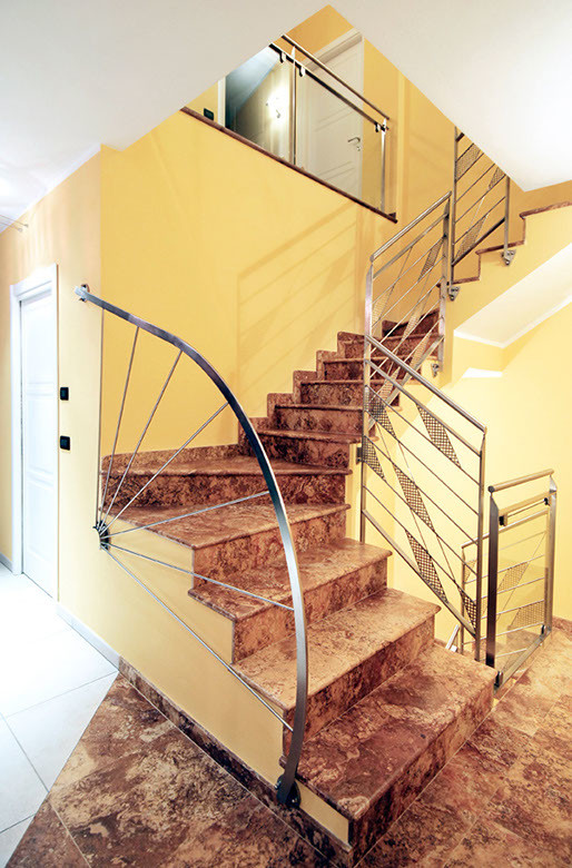 Foto de escalera en L contemporánea con escalones de mármol, contrahuellas de mármol y barandilla de metal