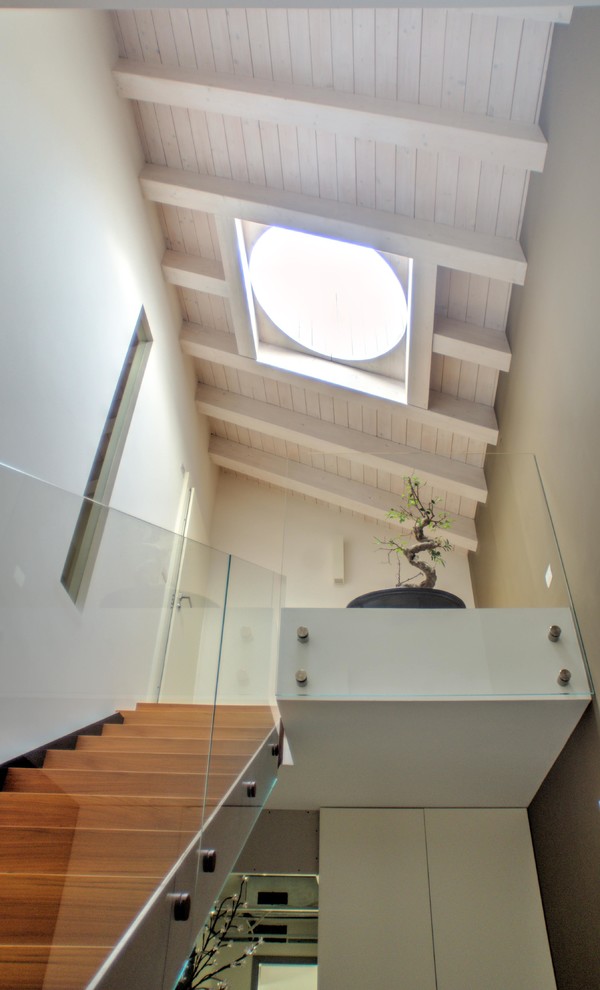 Diseño de escalera en L contemporánea de tamaño medio con escalones de madera, contrahuellas de madera y barandilla de vidrio
