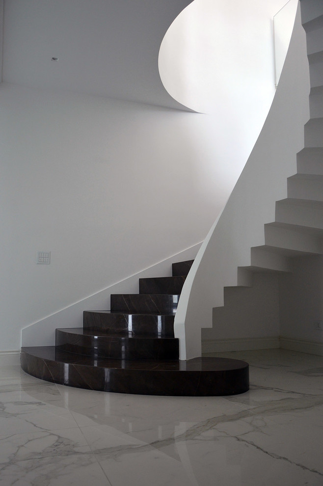 Inredning av en modern mycket stor svängd trappa i marmor, med sättsteg i marmor