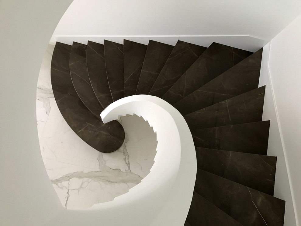 Modern inredning av en svängd trappa i marmor, med sättsteg i marmor
