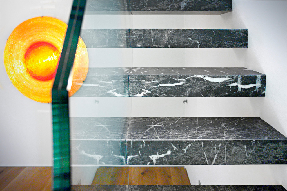 Foto de escalera recta actual de tamaño medio con escalones de mármol y barandilla de vidrio
