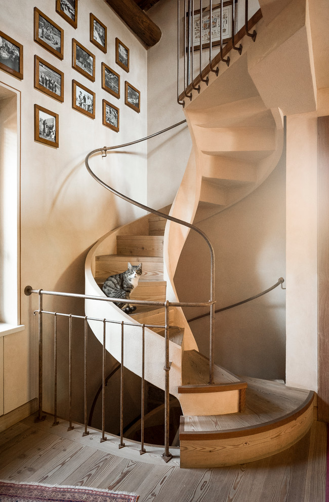 Стильный дизайн: изогнутая деревянная лестница в стиле кантри с деревянными ступенями - последний тренд
