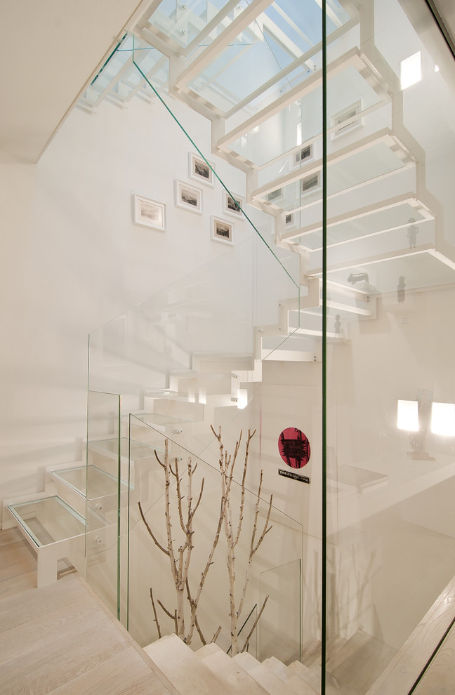 Modern inredning av en u-trappa i glas, med räcke i glas och öppna sättsteg