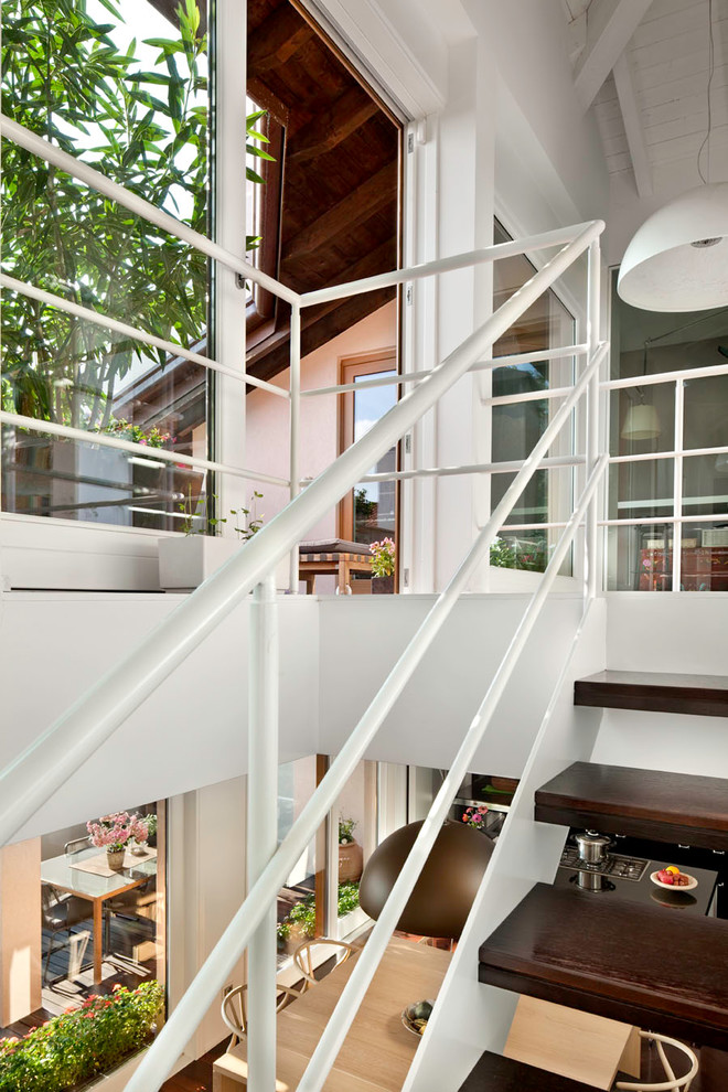 Réalisation d'un escalier sans contremarche courbe design de taille moyenne avec des marches en bois et un garde-corps en métal.