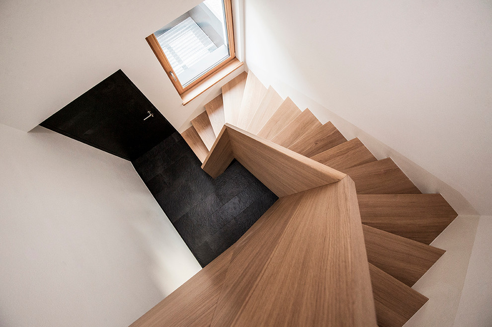 На фото: угловая лестница в современном стиле с деревянными ступенями и деревянными перилами с