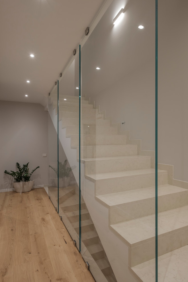 На фото: прямая лестница среднего размера в современном стиле с мраморными ступенями, подступенками из мрамора и стеклянными перилами