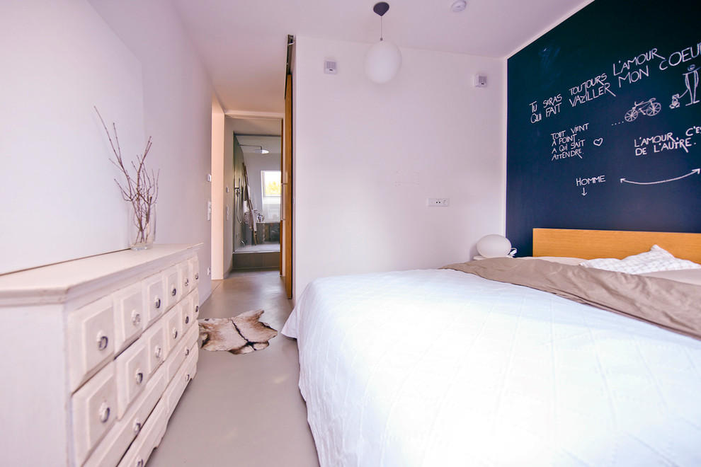 Kleines Modernes Hauptschlafzimmer ohne Kamin mit schwarzer Wandfarbe und Betonboden in München